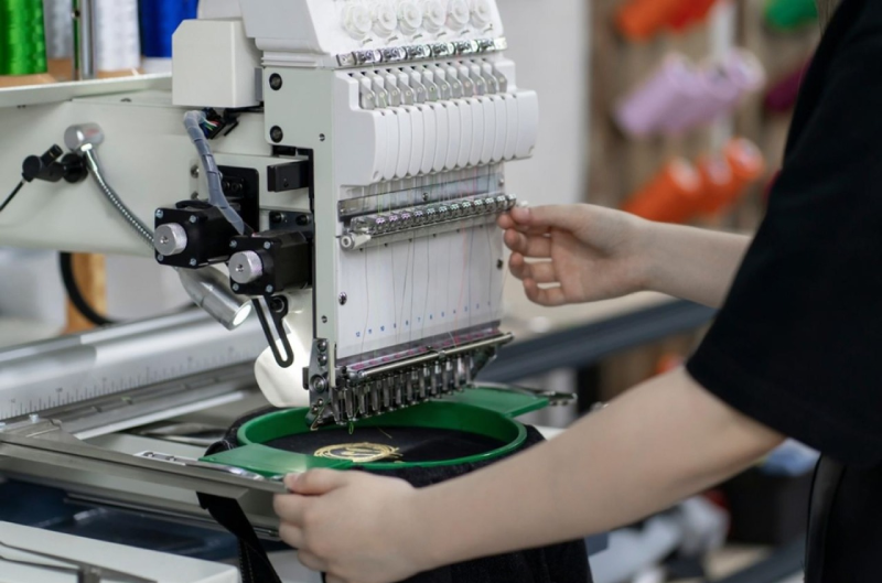 Industrial embroidery machine direct stitching anime design onto hoodie fabric for premium embroidered quality.